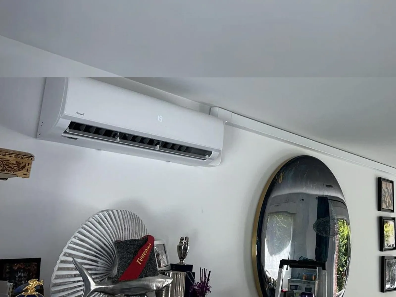 Le même séjour avec un split mural posé en haut du mur, liaisons frigorifiques cachées dans une goulotte peinte.