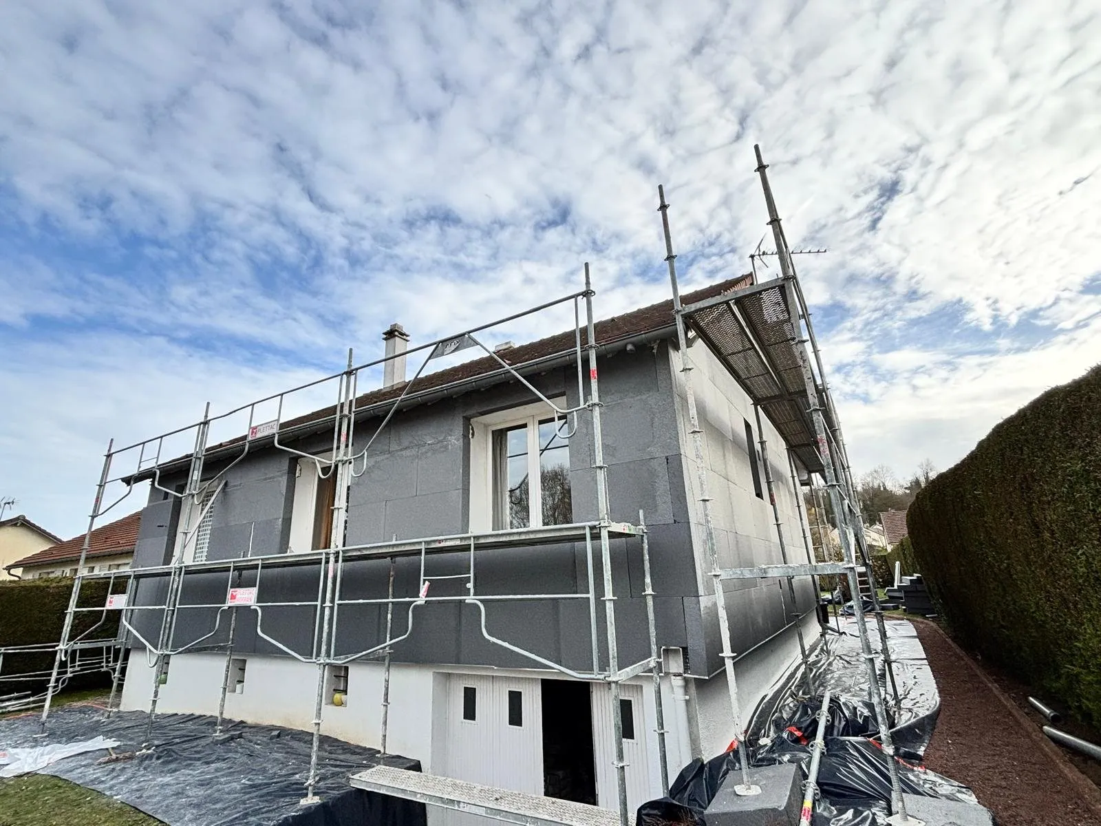 Isolation extérieure : pavillon bardé d'isolant gris sous échafaudage