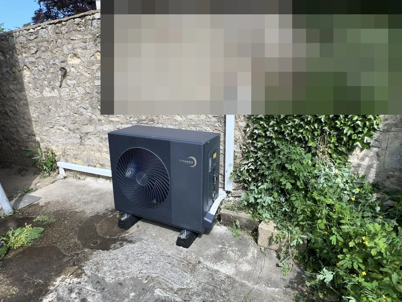 Pompe à chaleur : groupe extérieur contre un mur en pierre
