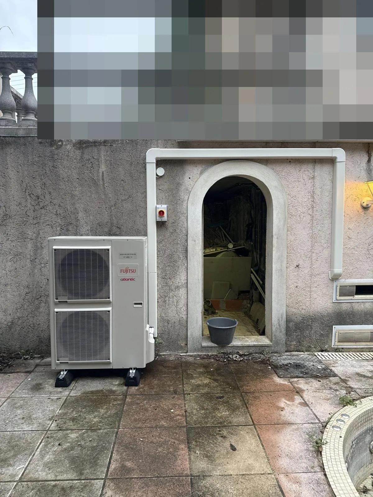 Pompe à chaleur : groupe extérieur fujitsu près d'une porte voûtée